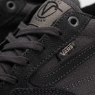 Close-up of the black Suede Rowan Vans Shoes (Skate Rowan Asphalt White VN0A5JICRP9), showing fabric texture, stitching, lace holes, and two Vans logos—one on the tongue and one on the side. Inspired by pro skater Rowan Zorilla.