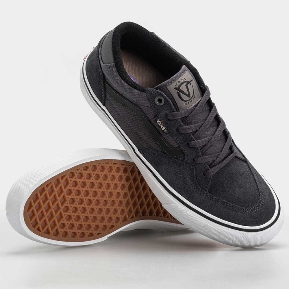 A pair of Vans Skate Rowan Asphalt White VN0A5JICRP9 Suede shoes is shown—one upright, one sideways to display the waffle-patterned sole. These black skate shoes have white soles, black laces, and the Vans logo on the tongue.