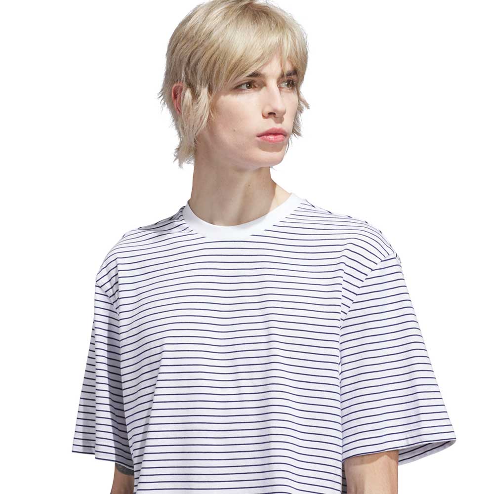 A person with short, blonde hair wears the Skate Yarn Dye Tee White Dark Blue (KC6291) from Adidas Skateboarding, featuring thin black horizontal stripes, and looks slightly to the side against a plain white background.