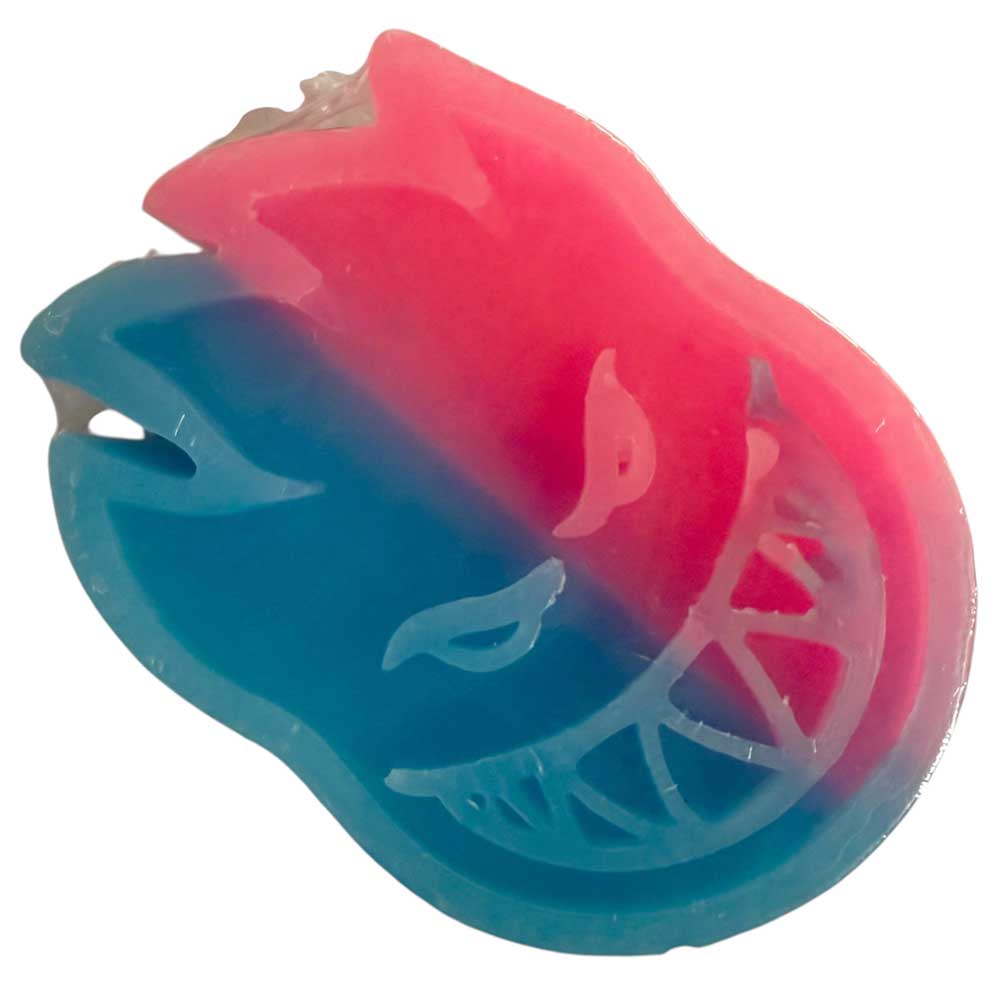 The Skateboarding Swirl Curb Wax Spitfire Wheels Swirl Pink Blue is a two-toned flame-face soap inspired by Spitfire Wheels, with a mischievous grin, featuring blue on the left, pink on the right—a tribute to classic skateboarding curb wax.