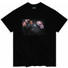 The Squeaky Violet Skateboards Black Tee is a black T-shirt featuring a slightly grainy, rectangular graphic of a person holding two plush toys—one pink and one purple—centered on the chest. The shirt includes VIOLET branding on the neck tag and is part of the Violet Skateboards collection, reflecting William Strobeck’s signature visual style.