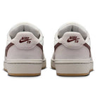 Back view of two Summit White Mystic Dates Code 58 IB0108102 Nike SB Skateboarding Suede Shoes, featuring off-white suede low-top silhouettes with dark red swoosh accents and logo embroidery on the heel tabs.