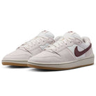 Summit White Mystic Dates Code 58 IB0108102 Nike SB Skateboarding suede sneaker in off-white with a dark red swoosh and a gum rubber sole.