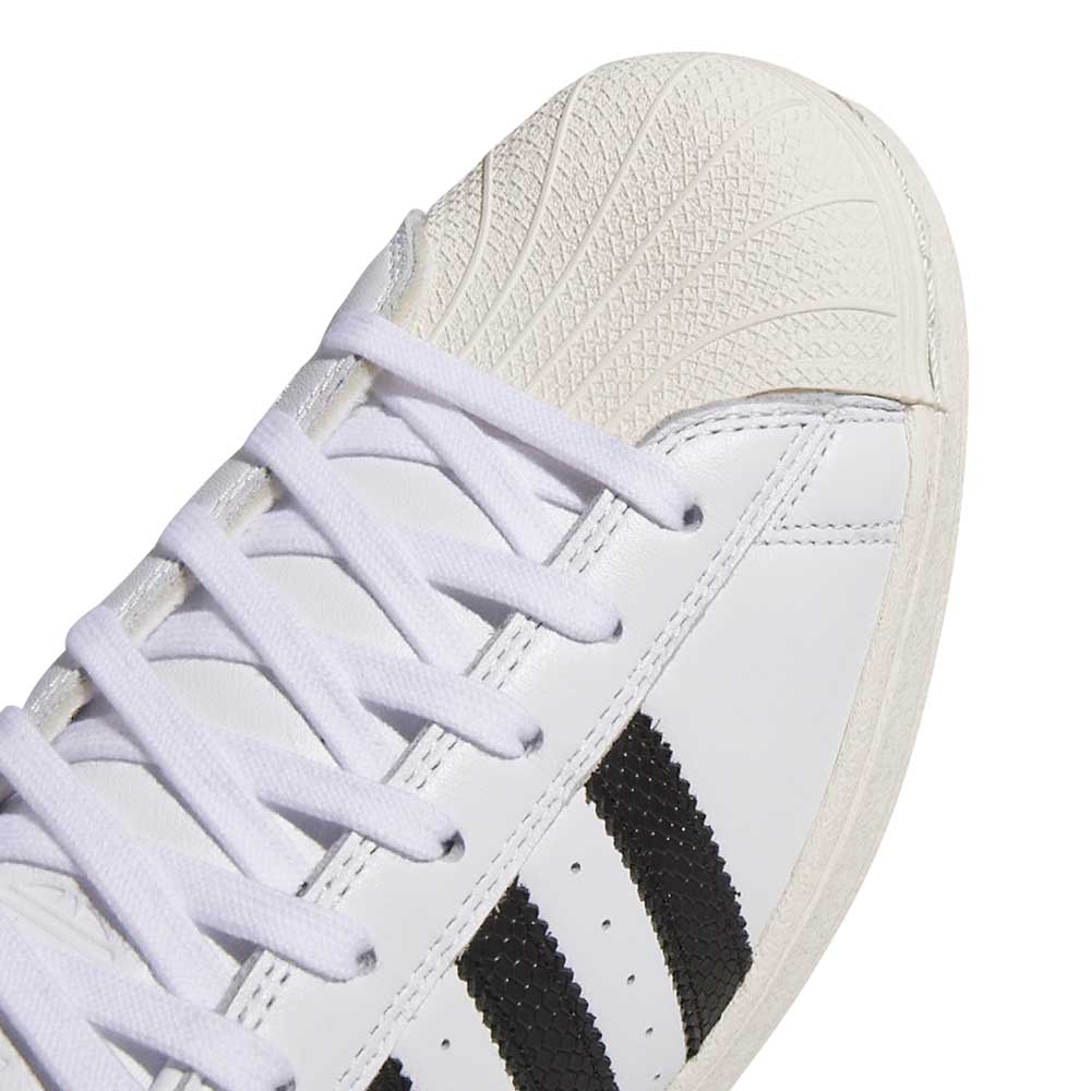 Close-up of the Superstar ADV White Black KI5727—adidas Skateboarding suede leather shoes—showing white laces, a textured off-white shell toe, and three black stripes for a classic look.