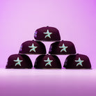 Six Swag Era 50th Camo Maroon Houston Astros New Era Hat 5950 Fitted caps are stacked in a pyramid against a pink and purple gradient background.