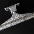 A close-up of the T Funk Polished Silver Standard INDY 169 Stage 11 Trucks Set of TWO, featuring engraved flames, snakes, and "FAITH"—an ideal choice for skateboarding truck fans and Tristan Funkhouser enthusiasts.