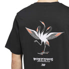 Wearing the TOS Crane Tee Black White KS4336 by Adidas Skateboarding, the individual sports a black skateboarding t-shirt adorned with an illustrated three-headed crane accented in red, standing on a skateboard. Stylized white “Temple of Skate” text and logos appear below the bird’s feet, showcasing this distinctive adidas collaboration.