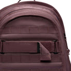 Close-up of the top section of the Tattoo Black Light Violet FD7544502 Nike SB RPM Skate Backpack, featuring mauve water-resistant fabric, a handle, zippers, and horizontal webbing straps with a Velcro patch.