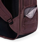 Close-up of the Tattoo Black Light Violet FD7544502 Nike SB RPM Skate Backpack’s maroon, water-resistant side pocket with partially open zipper, revealing a light gray lining, small compartments, and a padded shoulder strap.