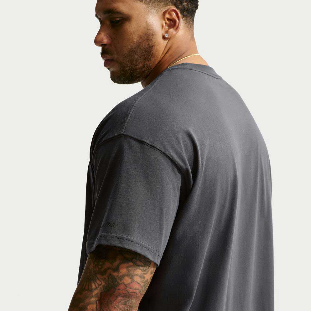 A man seen from the side wearing a charcoal gray Tee Black IW3134060 T-Shirt Nike SB Skateboarding.