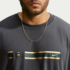 Close-up of a person wearing a grey Tee Black IW3134060 T-Shirt Nike SB Skateboarding, featuring a horizontal chest band with a logo and a swoosh.