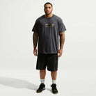A man wearing a black Tee Black IW3134060 T-Shirt Nike SB Skateboarding with a small horizontal graphic on the chest, paired with black cargo shorts, white socks, and black sneakers.