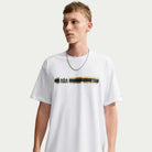 A man wearing a white Tee White IW3134100 T-Shirt Nike SB Skateboarding featuring a horizontal black and gold band across the chest with a crest and a small logo.