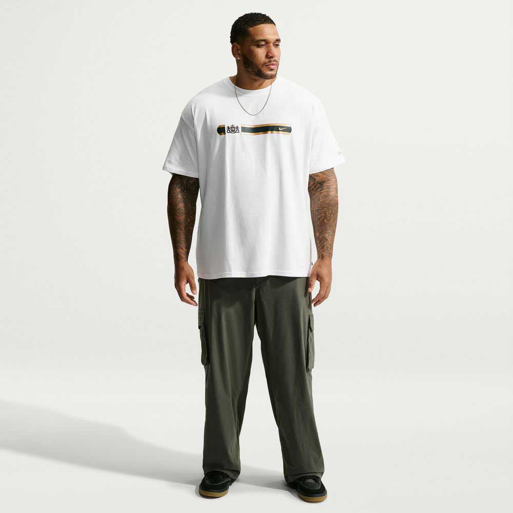 A man wearing a Tee White IW3134100 T-Shirt Nike SB Skateboarding with a horizontal graphic on the chest and olive green cargo pants.