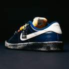 A pair of Zoom Tennis Classic x Rassvet IO9846400 Blue Void Sail Nike SB leather skateboarding shoes with a navy blue and white upper, unique patterns, yellow accents, and a speckled black-and-white sole is displayed against a dark background. Designed as premium skate shoes, they also feature a cushioned Solarsoft insole for enhanced comfort.