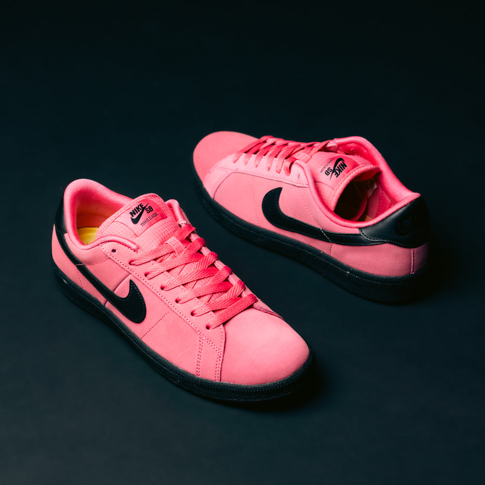 A pair of Zoom Tennis Classic IO8394600 Hyper Pink Black Nike SB leather skateboarding shoes, featuring black soles and black swoosh logos, displayed on a dark background.