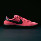 The Zoom Tennis Classic IO8394600 Hyper Pink Black Nike SB Leather Skateboarding Shoe is displayed in profile against a dark background, showcasing its bold red upper from the SB FC Pack, with a contrasting black Nike Swoosh logo, black heel, black outsole, and matching red laces.