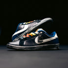 A pair of Zoom Tennis Classic x Rassvet IO9846400 Blue Void Sail Nike SB leather skateboarding shoes, featuring rainbow-colored lace loops, blue lining, textured soles, and a metallic tag on one shoe, are displayed against a dark background.