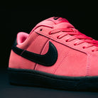 A close-up of the Nike SB Zoom Tennis Classic IO8394600 Hyper Pink Black Leather Skateboarding Shoe, featuring a bold black swoosh and black sole, with Hyper Pink laces and precise stitching detail, set against a dark background.
