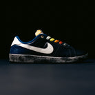 A pair of Zoom Tennis Classic x Rassvet IO9846400 Blue Void Sail Nike SB leather skateboarding shoes, featuring a dark blue upper, white Nike swoosh, textured black-and-white sole, Solarsoft insole, and rainbow-colored laces, is displayed against a black background—ideal for anyone seeking stylish and comfortable skate shoes.