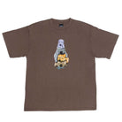 The Dogs Tee Washed Brown April Skateboards T-Shirt is a heavyweight brown tee with a unique garment-dyed look, featuring a graphic of a purple dog, gray dog, and yellow cat stacked above blue text.