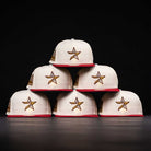 Six white The Final Hour New Era Hat 5950 Fitted NEW YEAR DROP caps with red brims and gold star logos are stacked in a pyramid against a black background, highlighting their bold style.