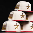 Six white The Final Hour New Era Hat 5950 Fitted NEW YEAR DROP caps with red brims are stacked in two rows. They feature a gold, black, and white star front logo, plus a Texas flag 2021 patch on the side, all set against a black background.