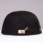 The Last Call New Era Hat 5950 Fitted NEW YEAR DROP seen from the back, black with small white embroidered stars and an orange-and-white rectangular patch near the bottom edge—a standout design.