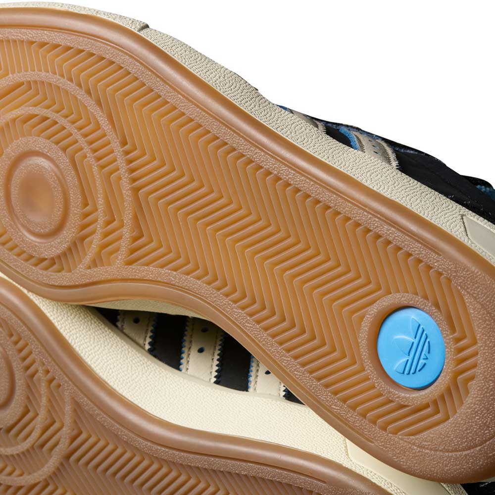 Close-up of the gum rubber outsoles on the Thrasher Magazine Glenburn Black Blue KH7384 Adidas Skateboarding Shoes, featuring a herringbone tread and blue circular heel logo. The premium leather upper has black, cream, and blue accents for durability.