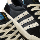 Close-up of Thrasher Magazine Glenburn Black Blue KH7384 Adidas Skateboarding Shoes featuring a black suede and leather upper, white laces, signature three stripes, blue stitching, and logo details for classic skate style.