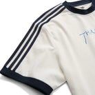 The Thrasher Magazine x Adidas AFA Tee White KX4548 by Adidas Skateboarding is a limited-edition white short-sleeve tee with black collar and sleeve trim, three black shoulder stripes, and blue chest embroidery.
