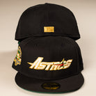 Two La Morenita Black 45th Houston Astros New Era Hat 5950 Fitted hats: the front hat has a gold embroidered Astros logo and colorful side patch, while the back displays a small gold rectangle on its rear panel.
