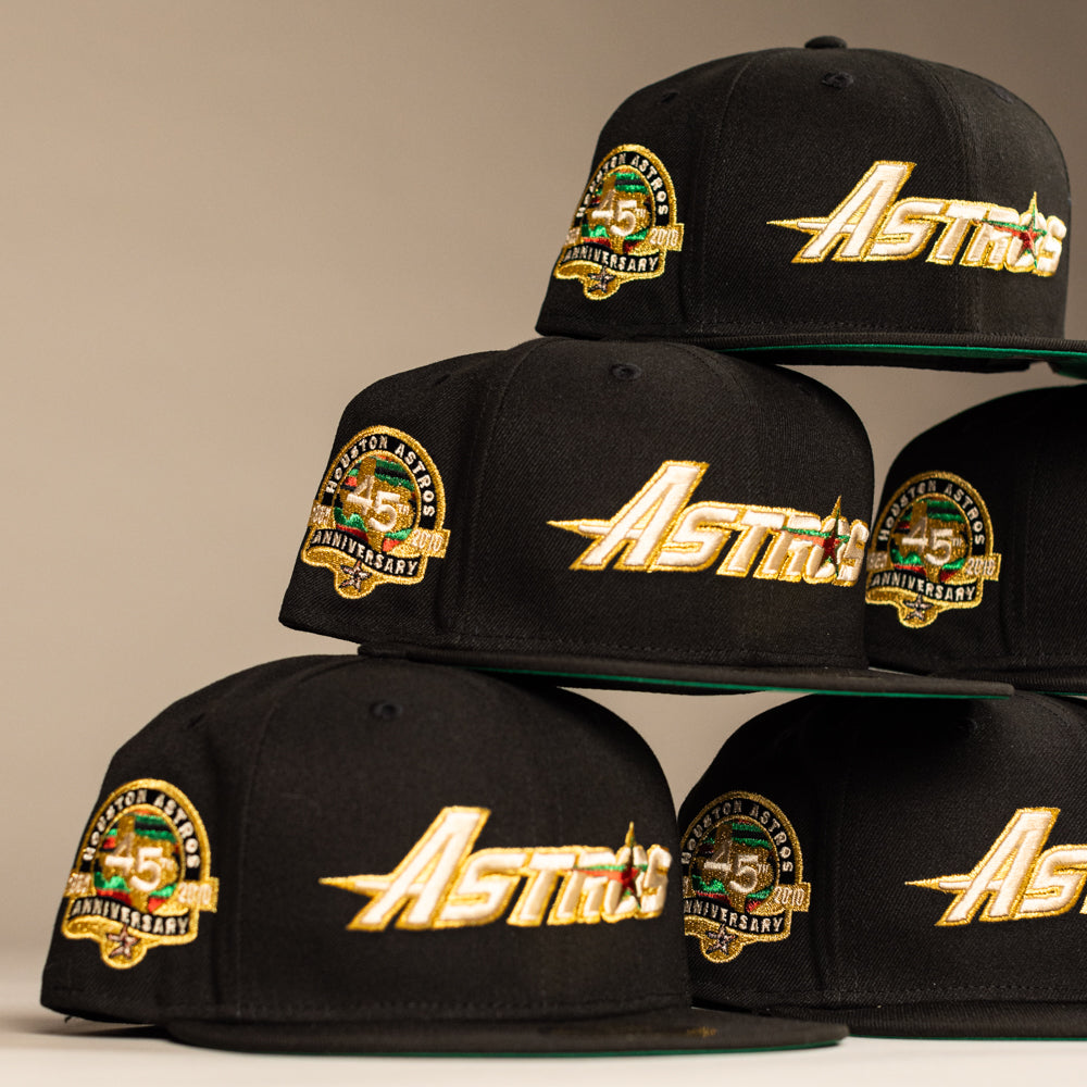 The La Morenita Black 45th Houston Astros New Era 5950 Fitted hat features a bold gold Astros logo, a green, yellow, and white 45th Anniversary side patch, and a flat brim.