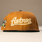 The El Gallo Canvas Bronze Black Houston Astros New Era 5950 Fitted Hat features bold Astros script on the front, a black brim, and a vibrant side patch—ideal for any Houston Astros fan.