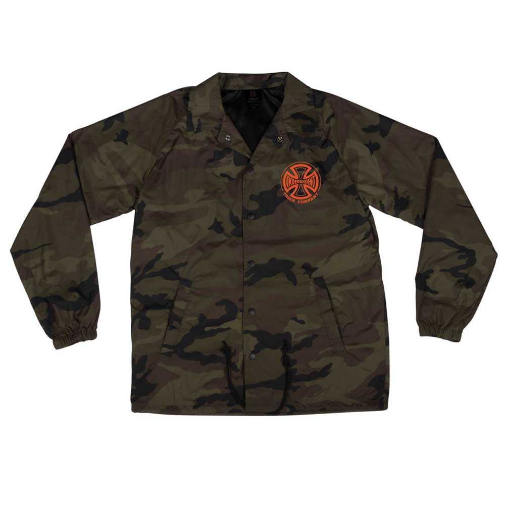 The Truck Co Legacy Coach Windbreaker Longsleeve Jacket for men features a camo design, snap buttons, and an orange circular emblem with a cross-like design on the left chest.
