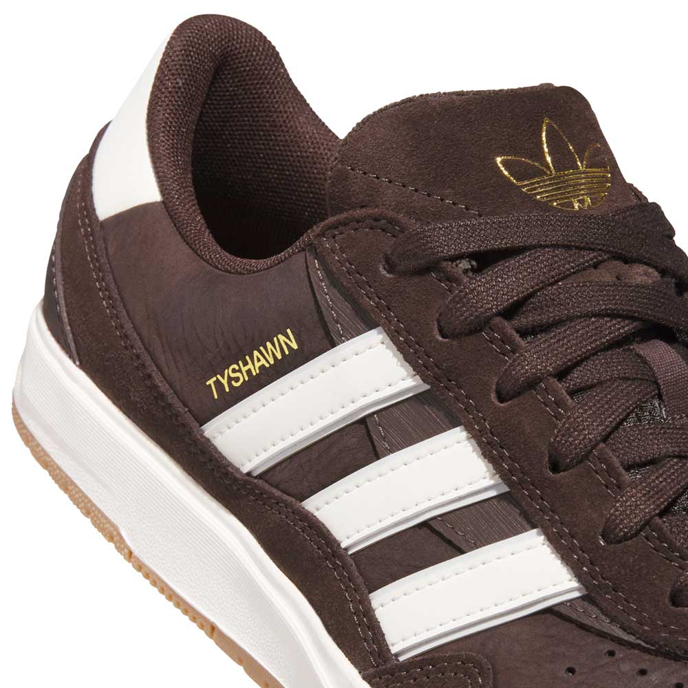 Close-up of the Tyshawn 2 II Brown White HQ4735 Adidas Skateboarding Shoe, featuring white stripes, gold TYSHAWN lettering, a white sole, and a gold adidas logo on the tongue.