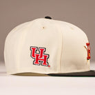 The Cougar 2.0 Houston Astros New Era Hat 5950 Fitted is cream-colored with a red and black UH logo on the side for the University of Houston, a dark green flat brim, and metal eyelets.