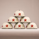 Six cream-colored The Cougar 2.0 Houston Astros New Era Hat 5950 Fitted caps, featuring a red and orange Astros logo, are displayed in a pyramid formation against a neutral backdrop.