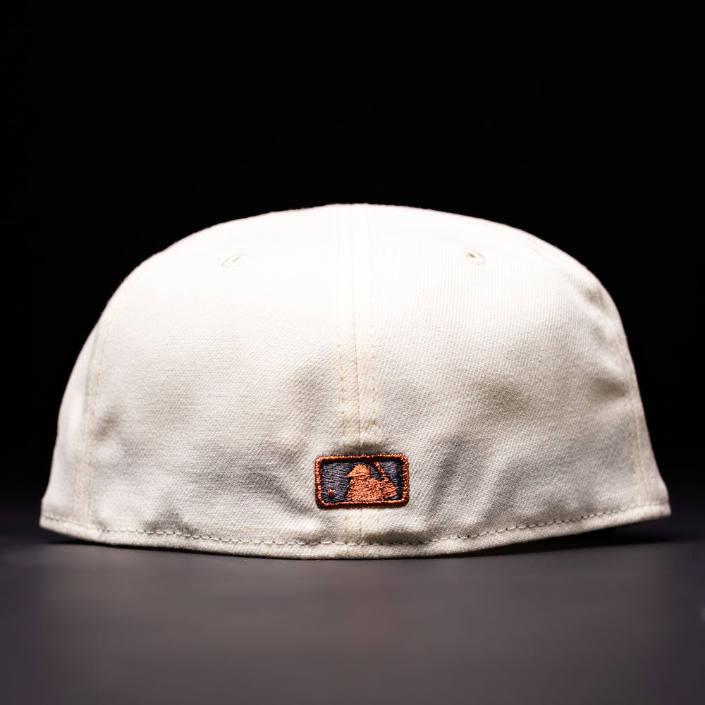 The Undaground 22WS Chrome Houston Astros New Era Hat 5950 Fitted is shown from the back in white, featuring a small rectangular patch with a black and orange logo, set against a dark background.