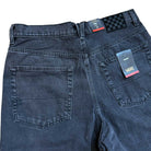 A close-up of the back of Vans Skate Check 5 Loose Shorts in washed black denim (VN000C9VEMQ1) shows two back pockets, attached Vans logo tags with size info, and a black-and-gray checkerboard patch on the waistband.