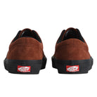 The back view of two brown suede Vans Skate Era Black Rust VN000ECR8D3 Suede Rubber Skateboarding Shoes with black soles, each featuring a red heel tab with white and black branding.