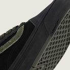Close-up of Vans Skate Half Cab Walnut Gum VN0A5FCD77J1 suede skate shoes in black, featuring a green textured stripe, black patterned sole with “DURACAP” near the toe, and PopCush cushioning for skate impact protection.