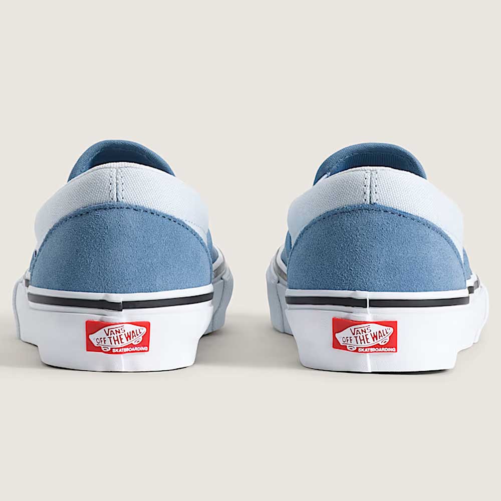 Rear view of two Vans Skate Slip On VN000EG5DSB1 Dusty Blue Suede Shoes featuring light blue suede uppers, white soles, and the classic red “Off the Wall” Vans logo on the heels, set against a neutral background. Engineered for skateboarding performance, these durable shoes combine iconic style with exceptional functionality.