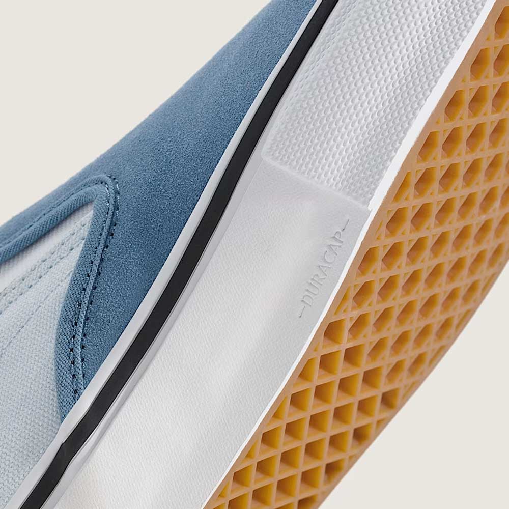 Close-up of the Vans Skate Slip On VN000EG5DSB1 Dusty Blue Suede Shoes’ sole, featuring a gum waffle pattern, white midsole, and light blue suede upper. The word DURACAP is embossed near the edge of the sole—an essential reinforcement feature that enhances durability and skateboarding performance.