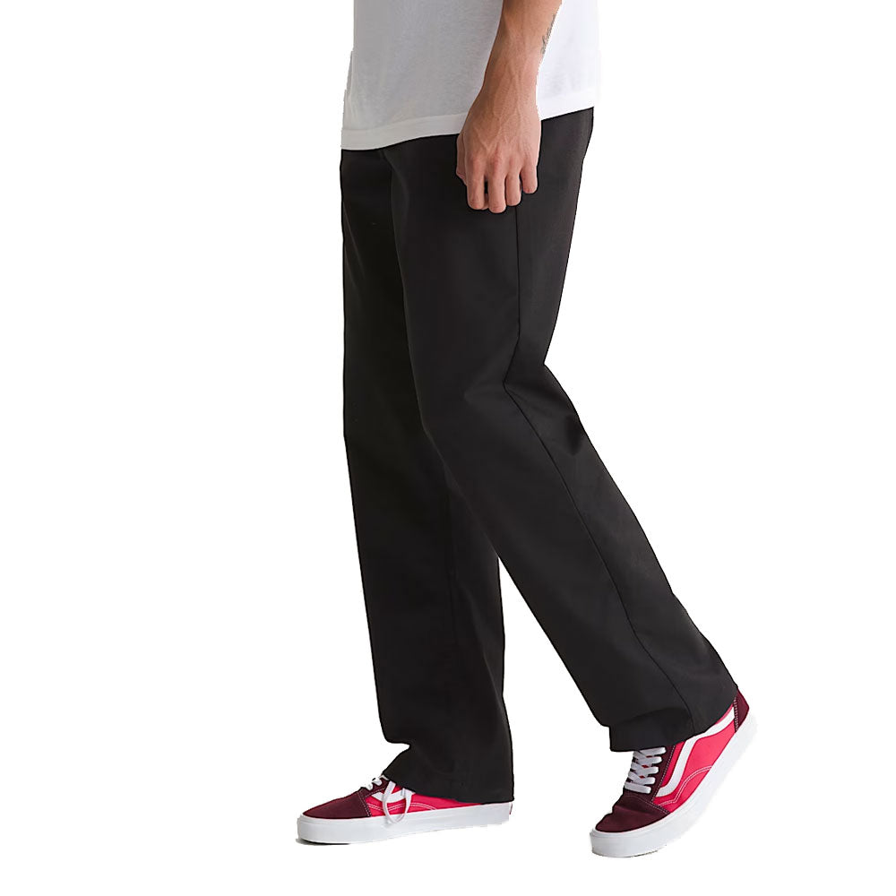 A person wearing Vans Straight Chino Black VN000TCXBLK1 Skate Check 5 Pants, a white t-shirt, and red sneakers with white soles stands against a plain white background. Only the lower half of the body is visible.