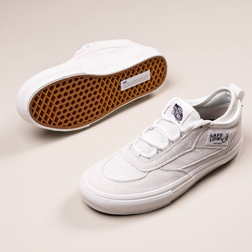 Two Skate Safe Low Blanc de Blanc VN000EG9JVY1 Vans shoes: both white with suede uppers, rubber soles, and white laces. One displays the SAFE LOW branding side view; the other shows a brown waffle-patterned outsole for superior grip and durability.