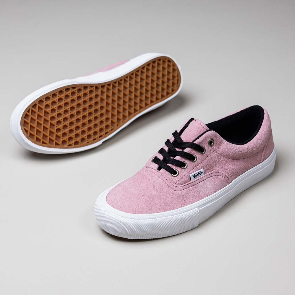 The Skate Era Mauve Mist VN000ECRZSB Vans Suede Rubber Shoes in pink feature white soles, black laces, and a textured brown sole for superior grip; one shoe stands upright while the other lies on its side to display the traction.