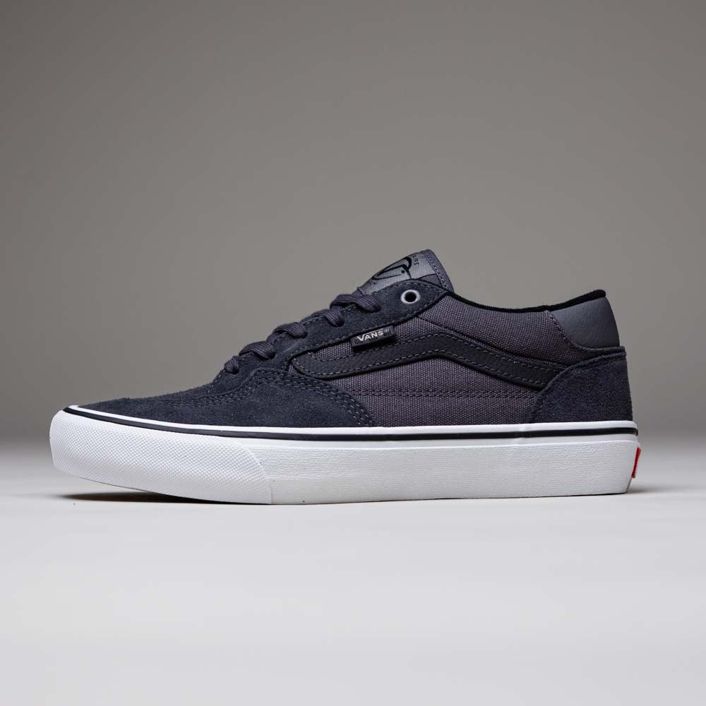 The Skate Rowan Asphalt White VN0A5JICRP9 Suede Vans shoe features a black low-top design, white sole, black laces, and the Vans logo on the side, inspired by Rowan Zorilla’s signature skate shoe, shown on a plain gray background.