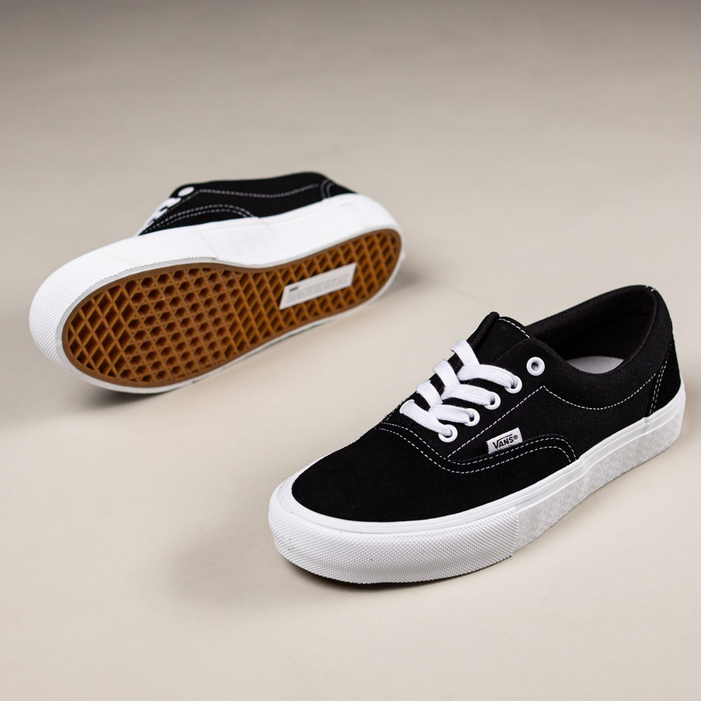 A pair of Skate Era Black White VN000ECRBA21 Vans suede rubber shoes, one upright and the other showing its brown waffle-patterned sole for excellent grip, featuring white laces and soles.