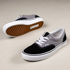 The Vans Skate Era Black Gray VN000ECRDE21 suede shoes feature black, gray, and white color blocking, white laces, and gum rubber waffle soles for superior grip, displayed on a light beige surface.
